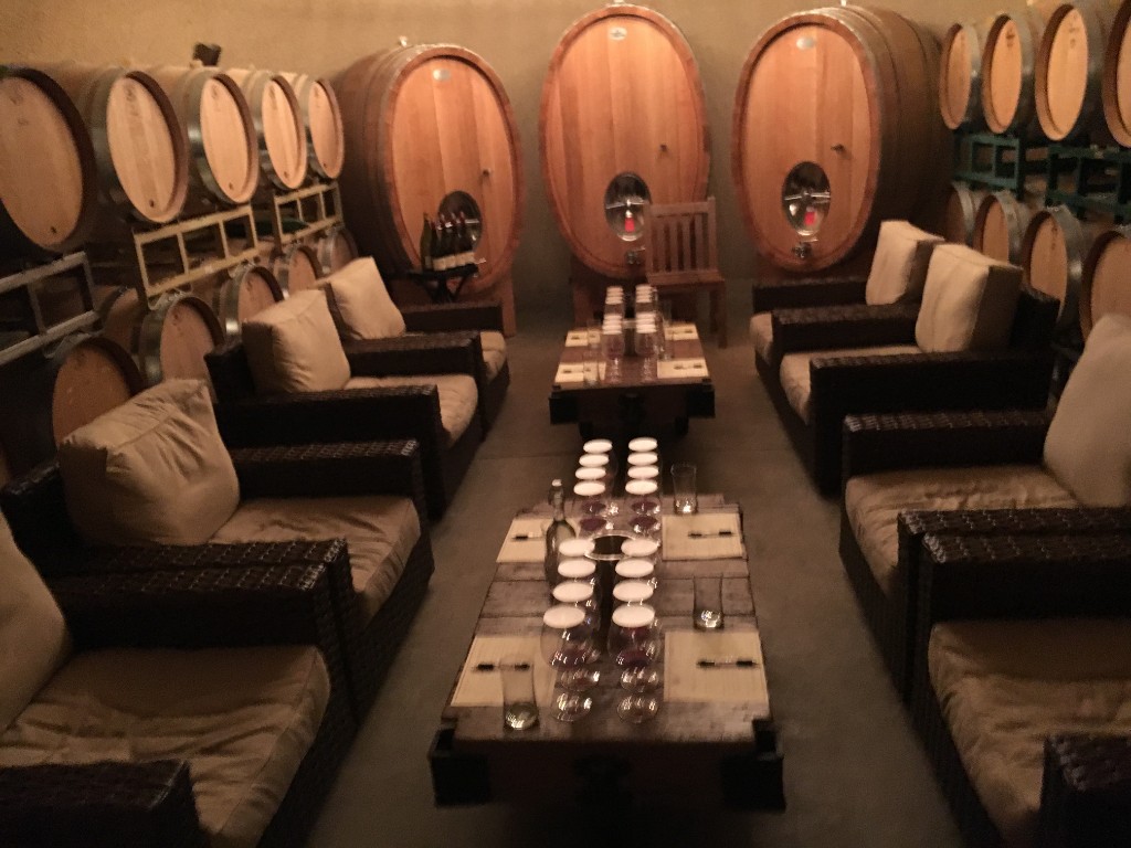 Intimate wine tasting setup among wooden barrels in a cellar