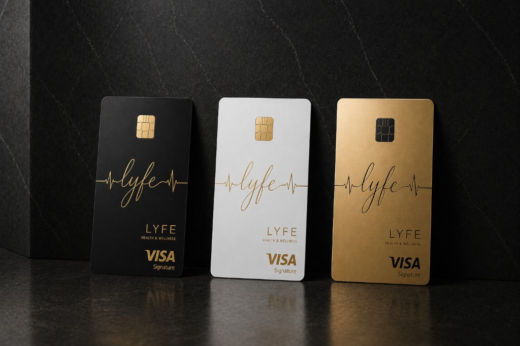 Three LYFE cards in black, white, and brushed gold standing on dark stone