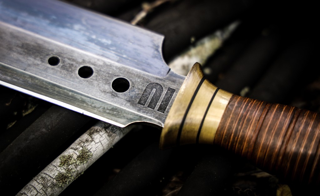 Macro photograph of knife blade, brass guard, and stacked leather handle