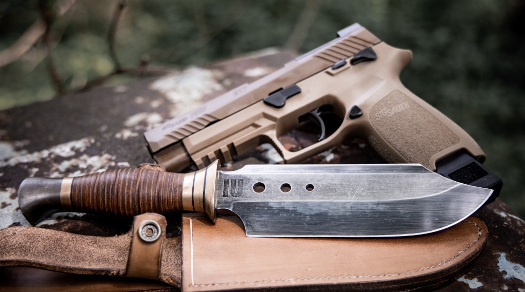 Knife and handgun on weathered metal surface