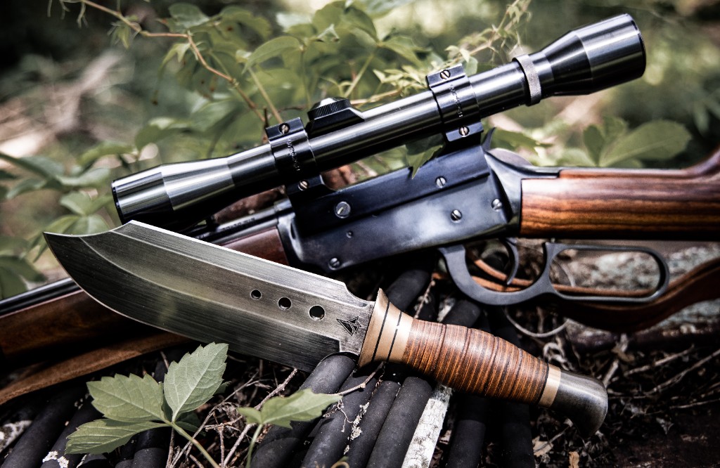 Custom fixed-blade knife with lever-action rifle in outdoor setting
