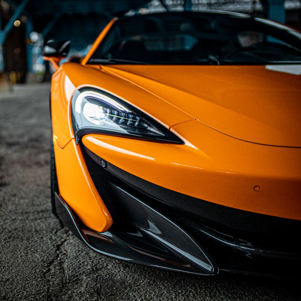 Front three-quarter view of orange McLaren highlighting headlight and front fascia