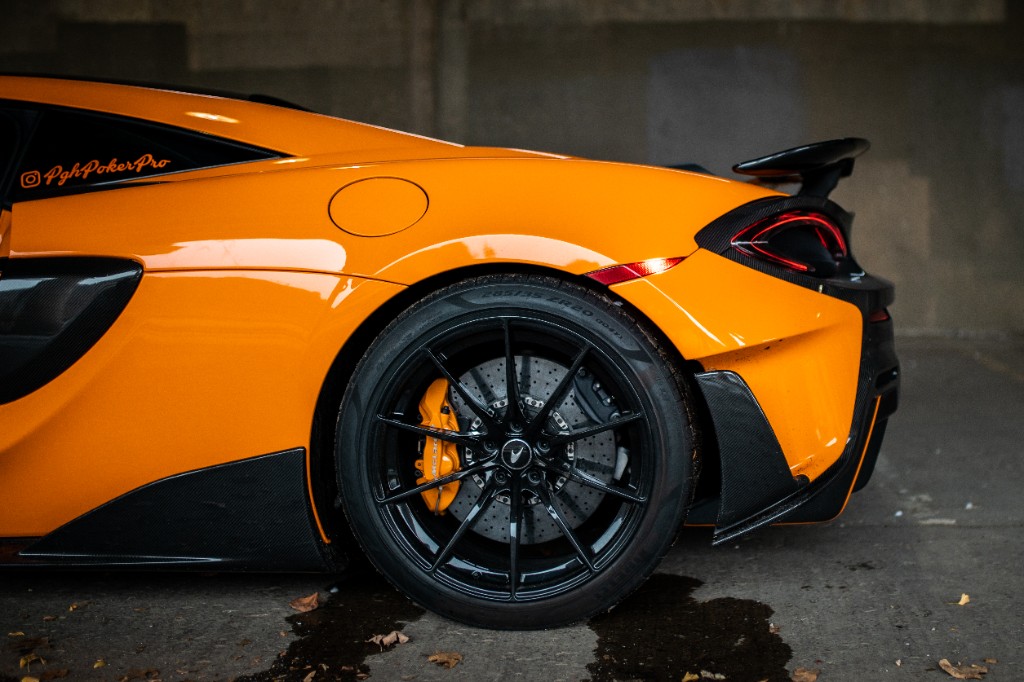 Rear-quarter close composition of orange McLaren showing wheel, tail light, and body surfacing
