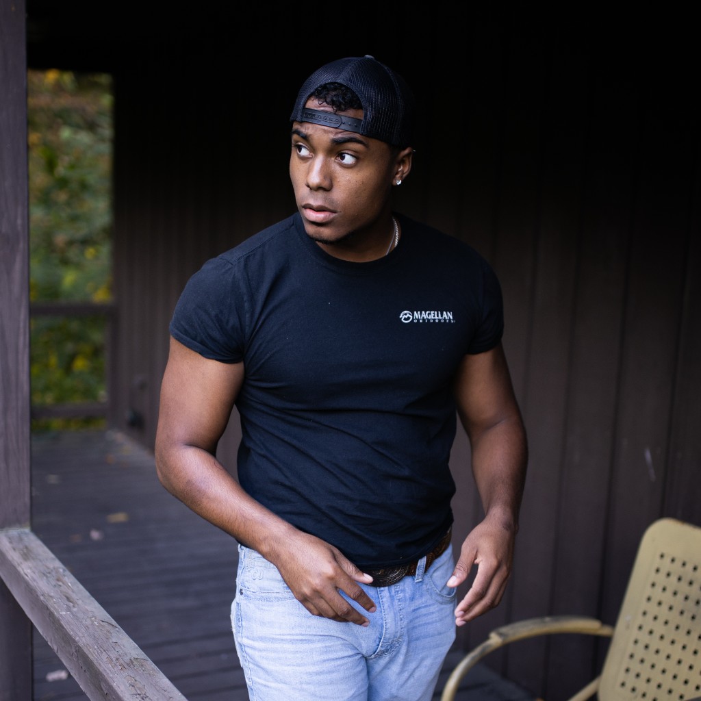 Tony Evans Jr. standing on a wooden deck in black t-shirt and jeans looking off camera