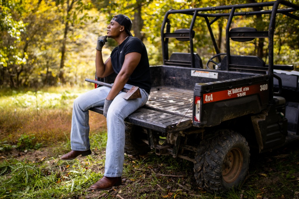 Tony Evans Jr. on UTV tailgate with axe resting on lap eyes closed