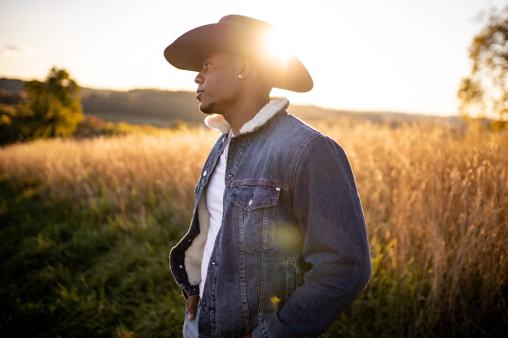 Tony Evans Jr. in profile wearing cowboy hat with sunset rim light in a field
