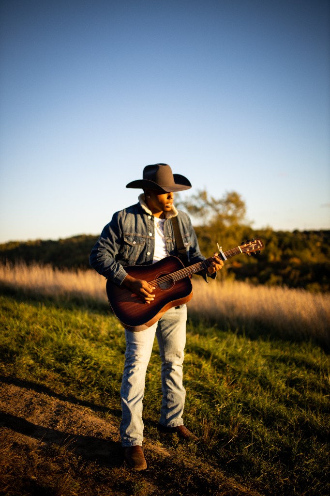 Vertical full-body Tony Evans Jr. playing guitar outdoors